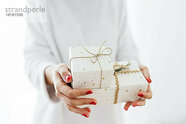 Frau überreicht Weihnachtsgeschenke vor weißem Hintergrund