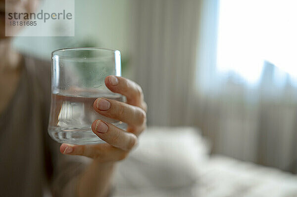 Frau hält zu Hause ein Glas Wasser