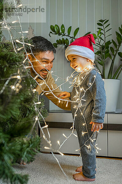 Netter Junge mit Vater  der zu Hause den Weihnachtsbaum schmückt
