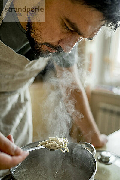 Mann untersucht heiße Suppe in der heimischen Küche