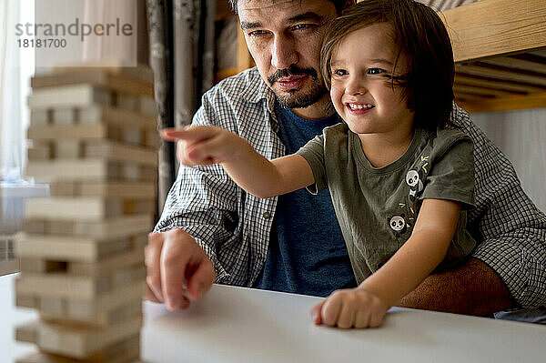 Neugieriger Junge spielt zu Hause mit seinem Vater ein Blockentfernungsspiel