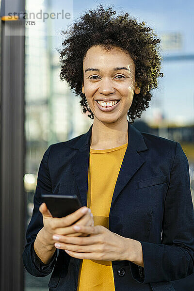 Lächelnde Geschäftsfrau im Blazer mit Mobiltelefon
