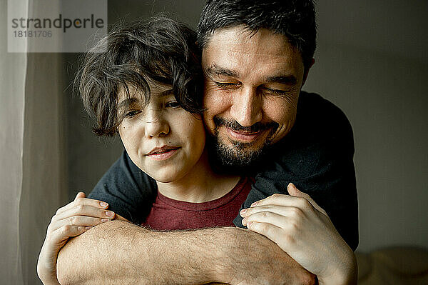 Lächelnder Vater umarmt Sohn zu Hause