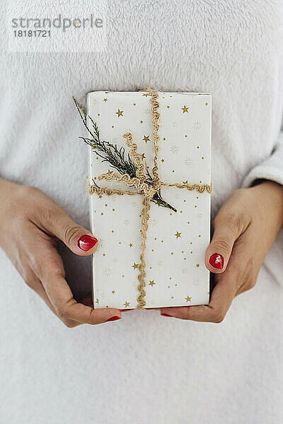 Hands of woman holding Christmas gift wrapped in white paper