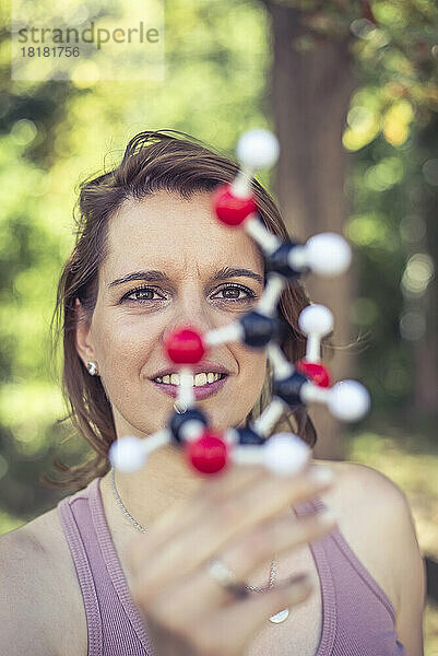 Lächelnde Frau untersucht Molekülmodell im Park