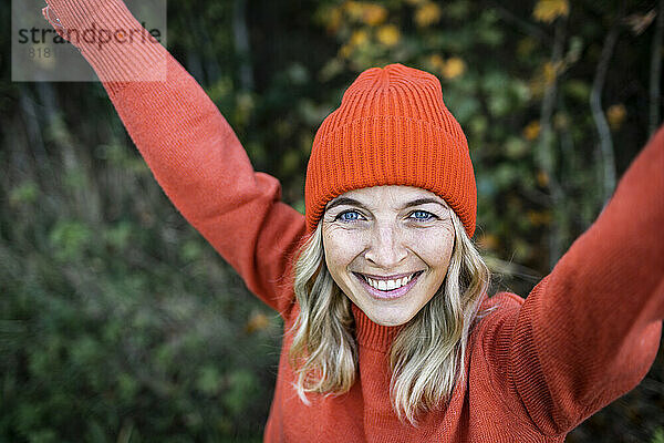 Lächelnde reife Frau mit orangefarbener Strickmütze am Wochenende