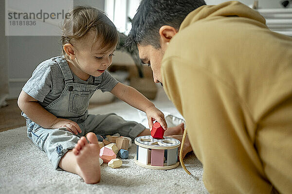 Vater und Sohn spielen zu Hause mit Holzspielzeug