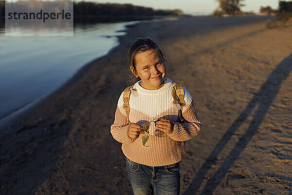 Lächelndes Mädchen im Pullover am Strand