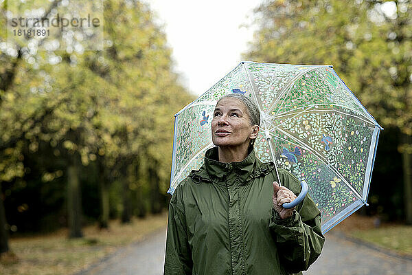 Nachdenkliche ältere Frau mit Regenschirm