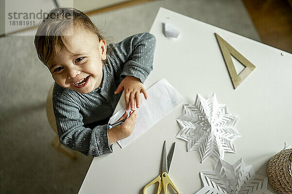 Glücklicher Junge mit Bleistift- und Papierzeichnung zu Hause
