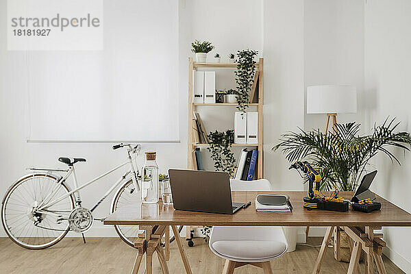 Moderne Technologien auf dem Schreibtisch mit Fahrrad und Gepäckträger im Hintergrund im Büro