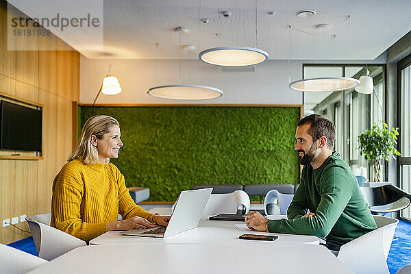 Lächelnde Geschäftskollegen  die einander im Büro anschauen