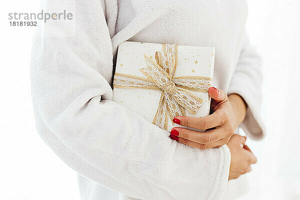Frau hält Weihnachtsgeschenk vor weißem Hintergrund