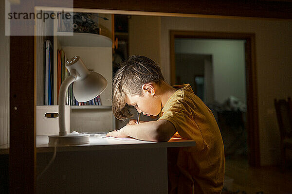 Student lernt zu Hause unter der Schreibtischlampe