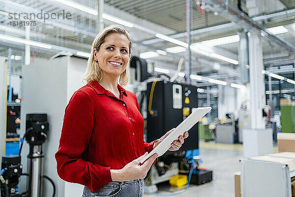 Glückliche Geschäftsfrau mit Tablet-PC in der Industrie