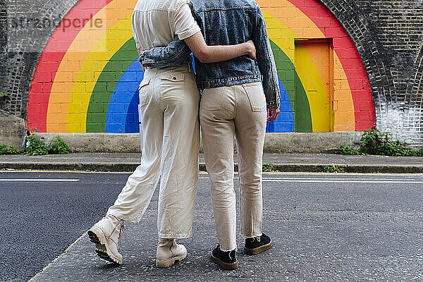 Schwules Paar vor regenbogenfarbener Wand