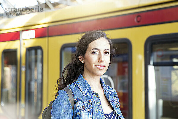 Germany  Berlin  portrait of young woman in front of city train