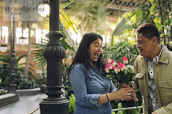 Lächelnder Mann schenkt Frau am Valentinstag Blumen