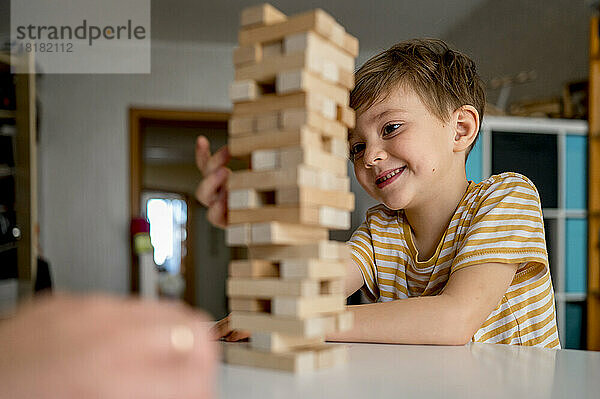 Lächelnder Junge  der zu Hause ein Blockentfernungsspiel spielt