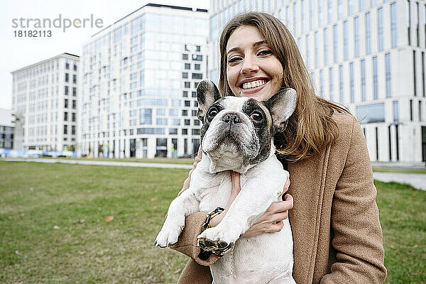 Glückliche Frau mit französischer Bulldogge vor Gebäuden