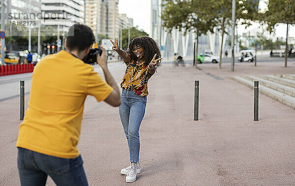 Junger Mann fotografiert Frau mit Kamera am Fußweg
