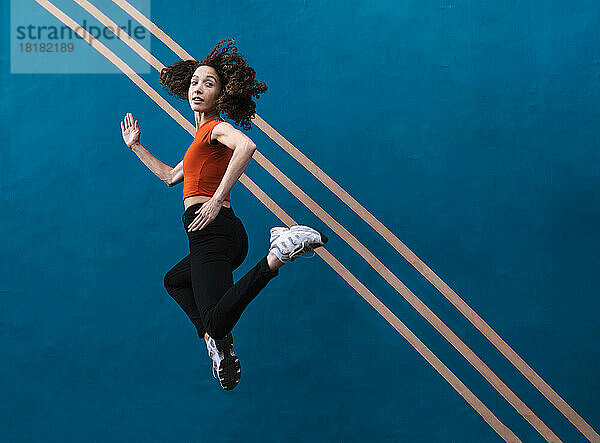 Frau springt vor blaue Wand