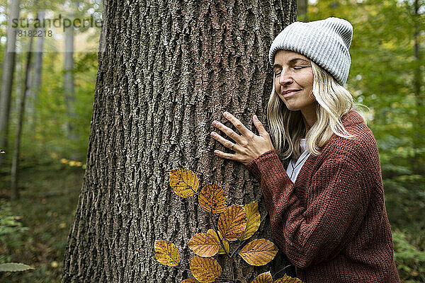 Reife Frau umarmt Baum im Herbstwald