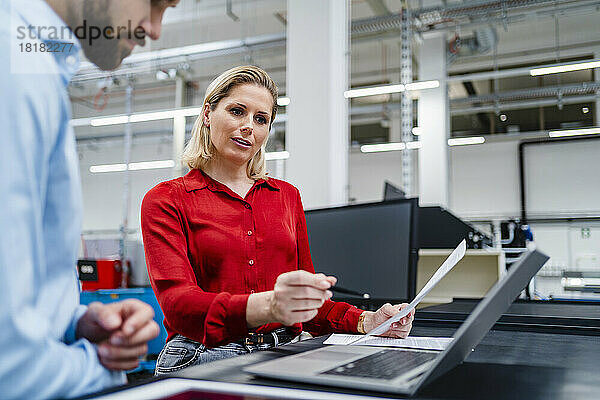Geschäftsfrau diskutiert mit Kollegin über Laptop in der Fabrik