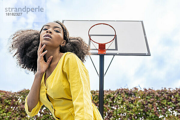 Selbstbewusste junge Frau steht vor dem Basketballkorb