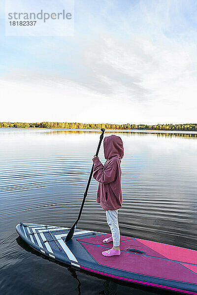 Mädchen trägt Kapuzenshirt auf Paddleboard im See