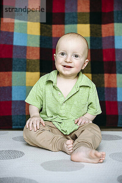 Happy cute boy sitting on carpet