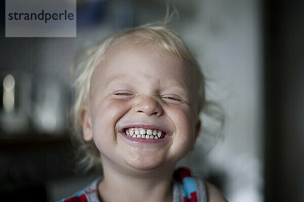 Porträt eines lachenden kleinen Jungen mit geschlossenen Augen