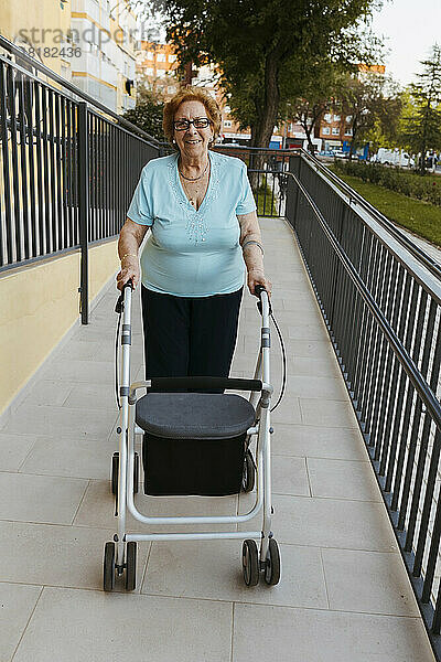 Lächelnde ältere Frau mit Gehhilfe auf Fußweg