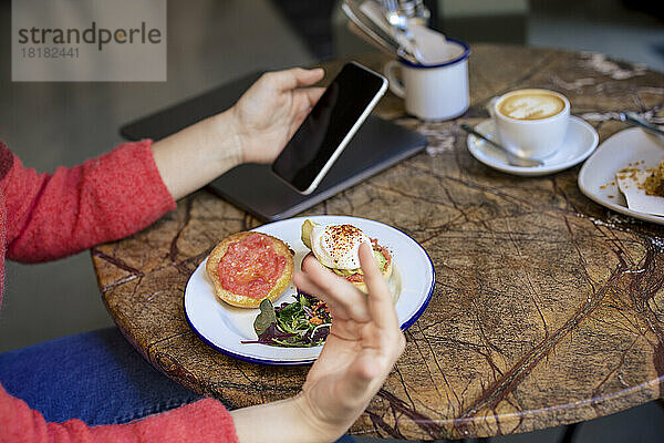 Freiberufler nutzt Smartphone am Tisch im Café