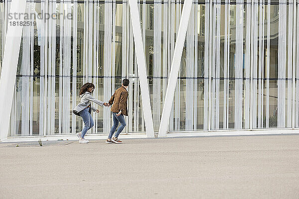 Sorgloses Paar rennt und genießt vor dem Gebäude