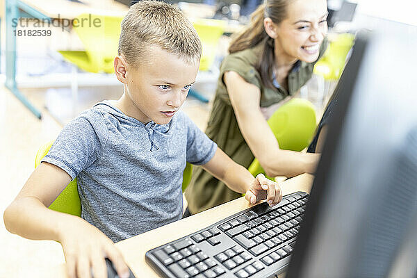 Konzentrierter Junge benutzt Computer im Unterricht in der Schule
