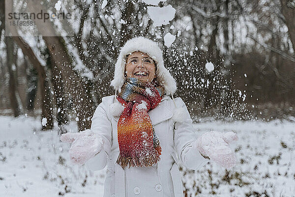 Glückliche Frau  die im Park mit Schnee spielt