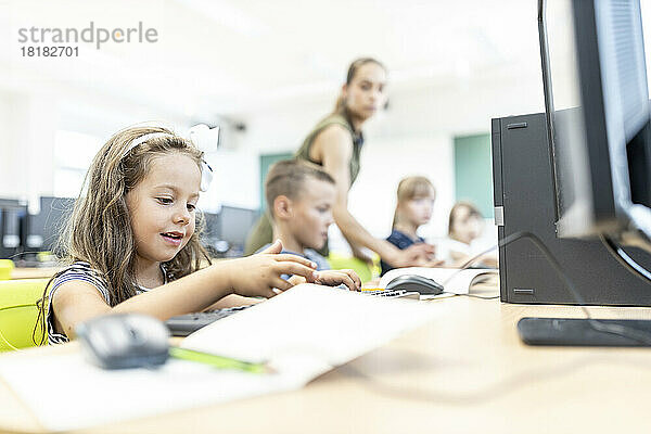Mädchen tippt im Computerunterricht in der Schule auf der Tastatur