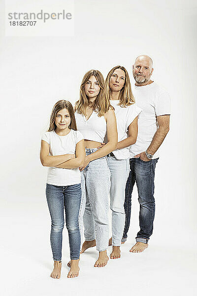 Selbstbewusste Familie mit zwei Kindern  die im Studio in einer Reihe stehen