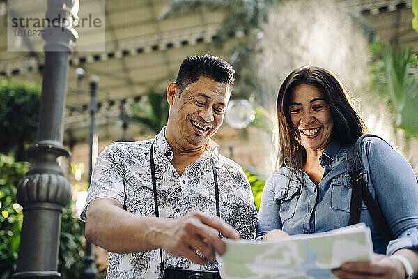 Happy mature couple on vacation looking at map