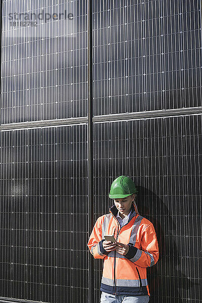 Ingenieurin nutzt Smartphone und stützt sich auf Sonnenkollektoren