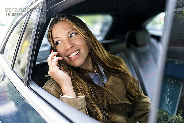 Lächelnde Geschäftsfrau  die im Auto mit dem Handy telefoniert