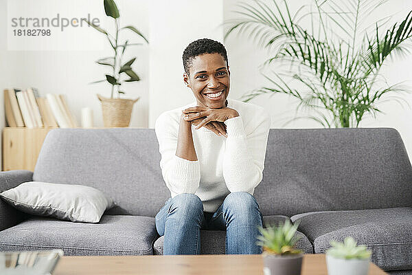 Porträt einer lächelnden Frau  die zu Hause auf der Couch sitzt