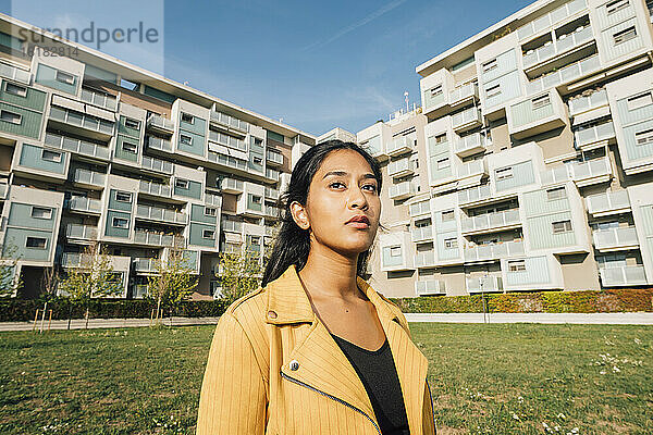 Young woman in front of residential buildings on sunny day