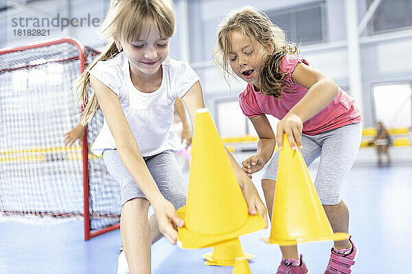 Verspielte Mädchen sammeln Kegel auf dem Schulsportplatz
