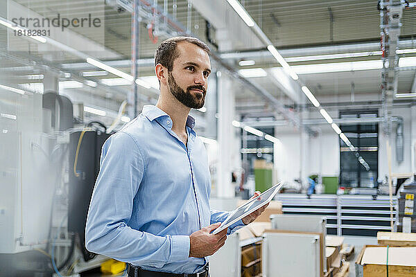 Lächelnder Geschäftsmann mit Tablet-PC in der Fabrik