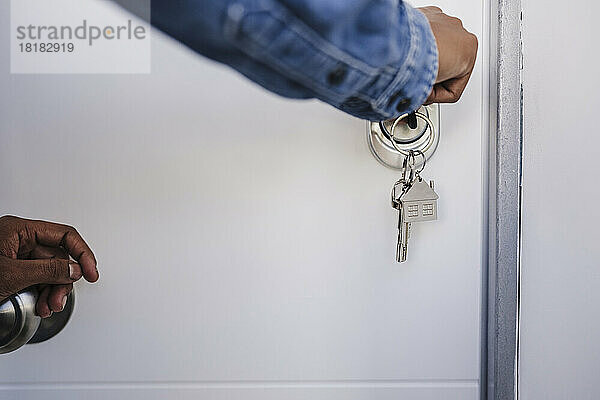Hand einer Frau  die die Tür mit Hausschlüsseln öffnet