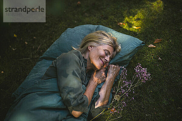 Lächelnde reife Frau  die im Garten schläft