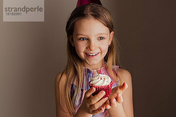 Porträt eines glücklichen kleinen Mädchens mit Cupcake