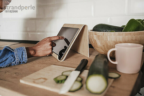 Hände einer Frau  die einen Tablet-PC an der Küchentheke benutzt